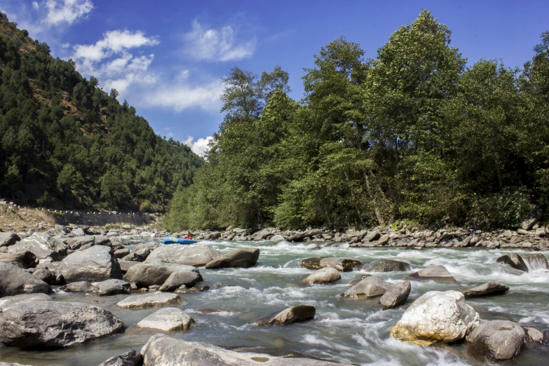 a man in a canoe in a river surrounded by rocks and green trees