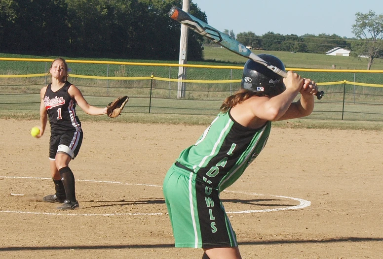 a woman swinging a softball bat at a ball