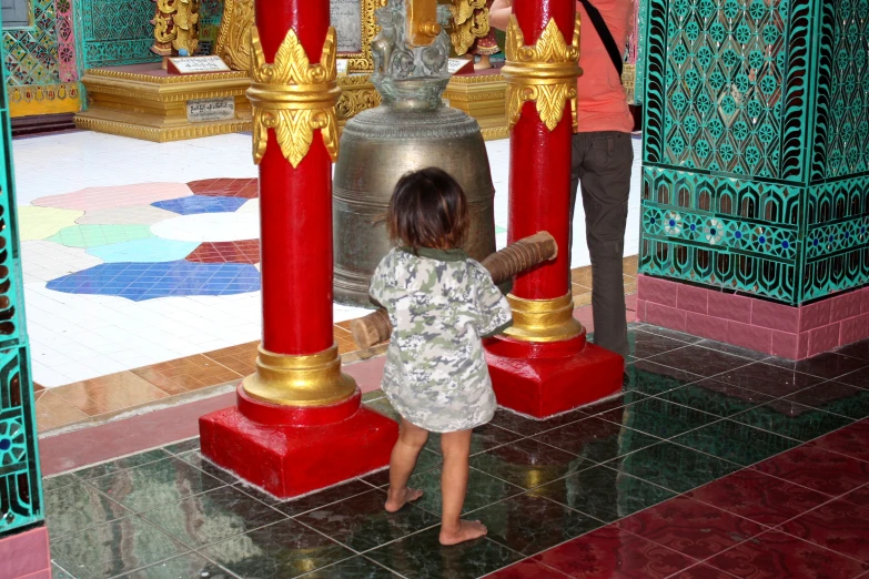 a child is standing next to a bell