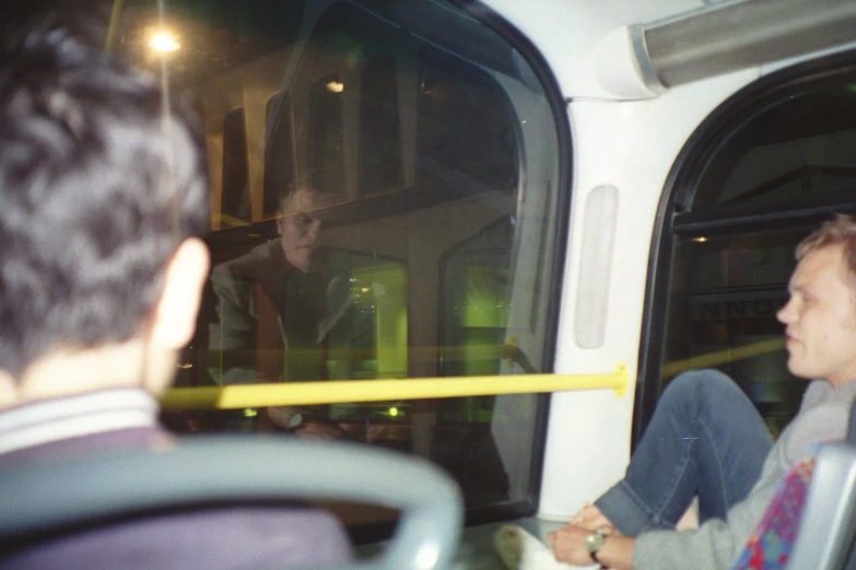 two people sitting on bus near the door of window