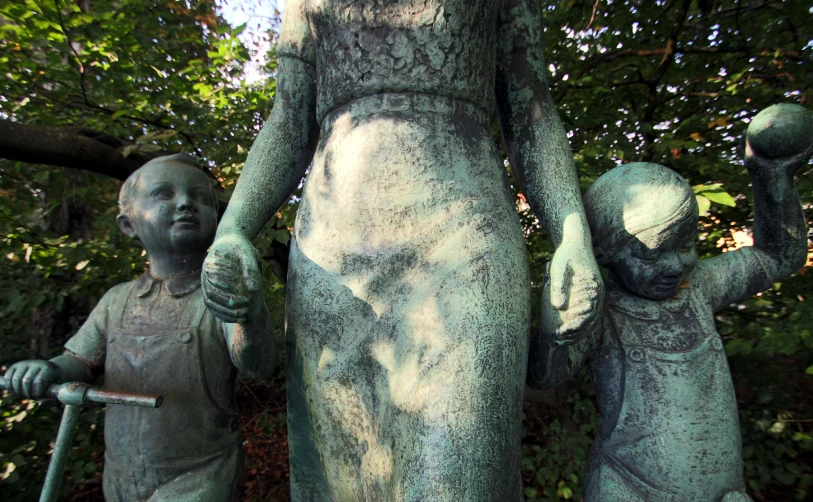 a statue of two people and a baby in the foreground