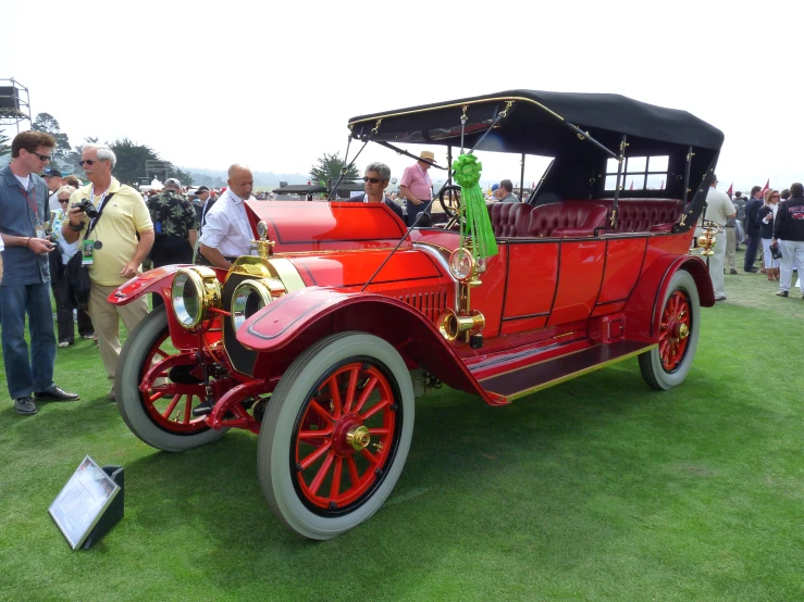an old red car sits on display during a show