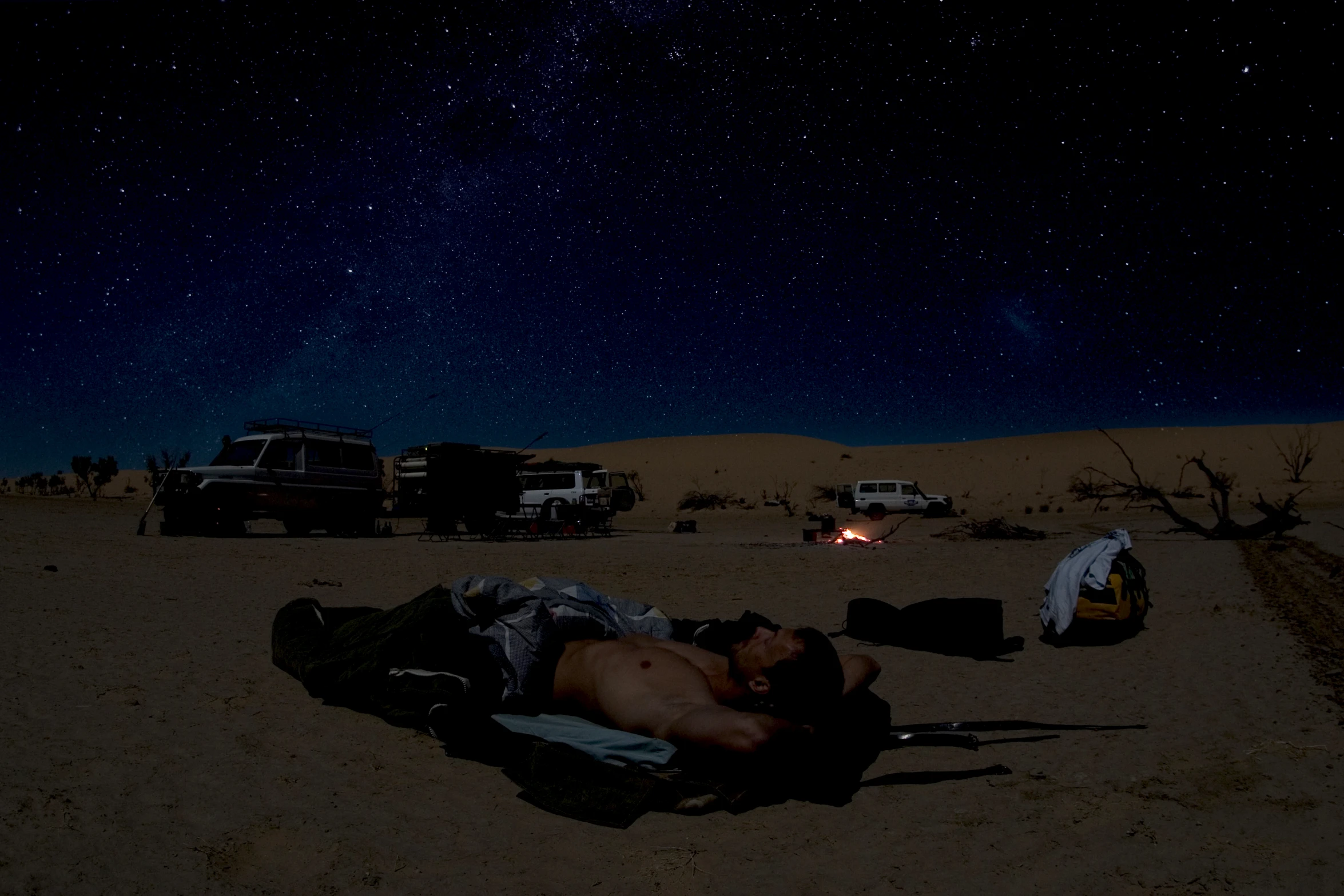 a person is sleeping on a blanket in the middle of a desert