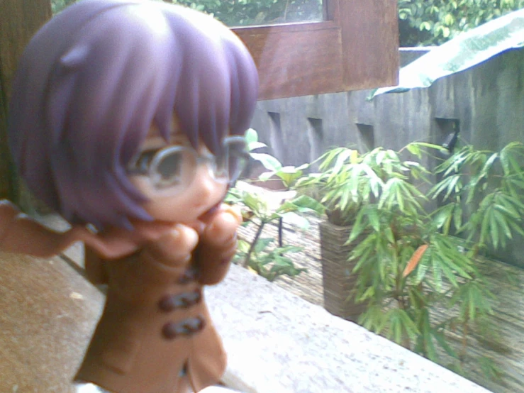 a figurine with purple hair holding his chin on his finger