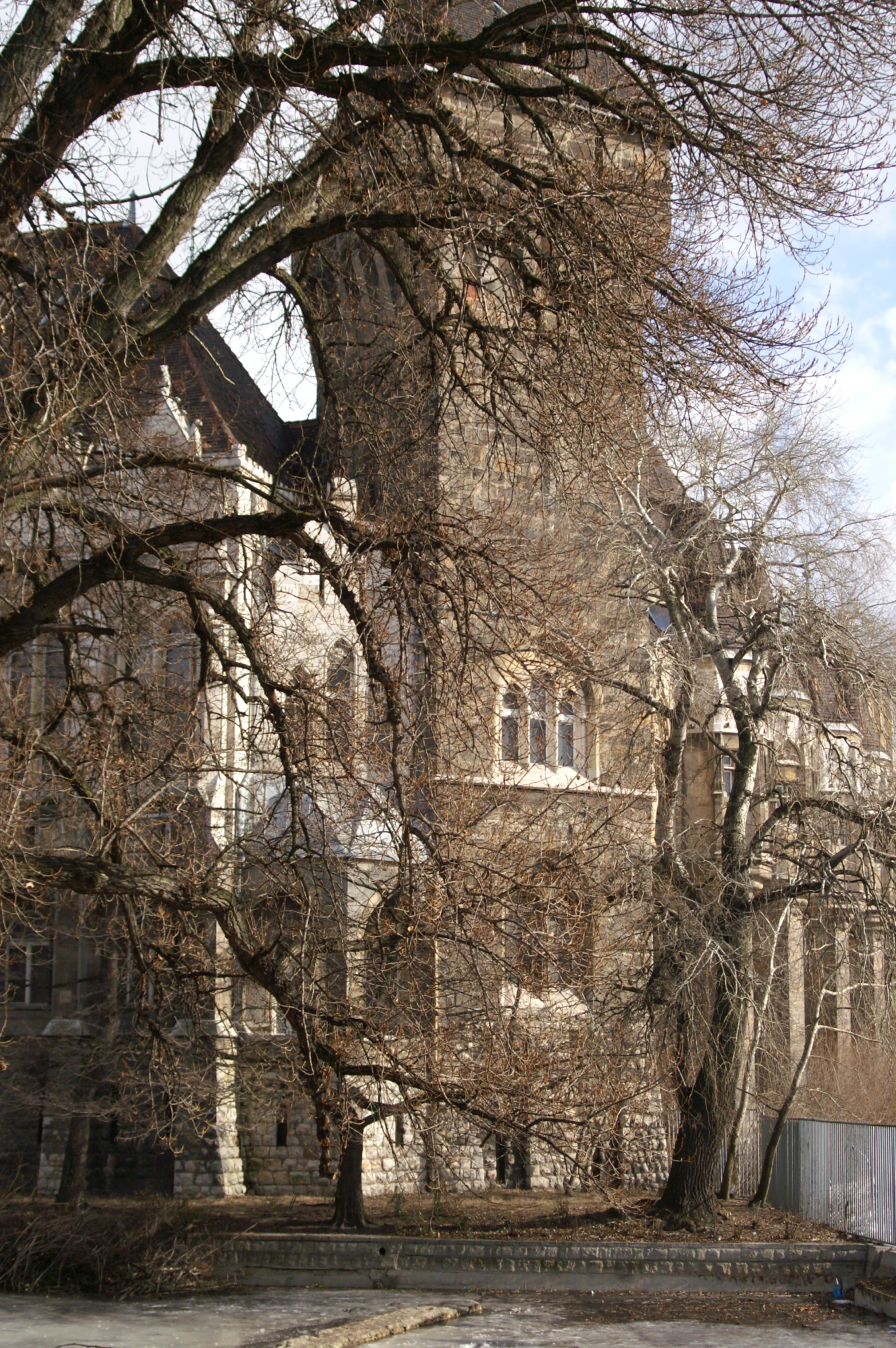 an old house with a fence and trees in front