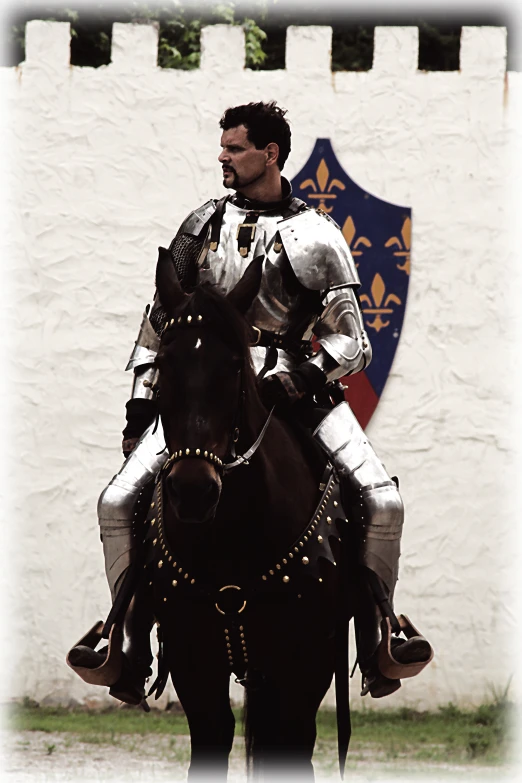 a man in armor riding a horse past a white fence