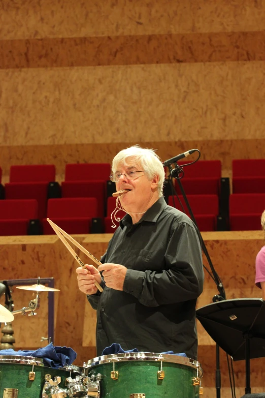 an older man plays music with instruments on a stage