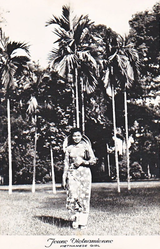 a woman standing in a field of grass near two palm trees