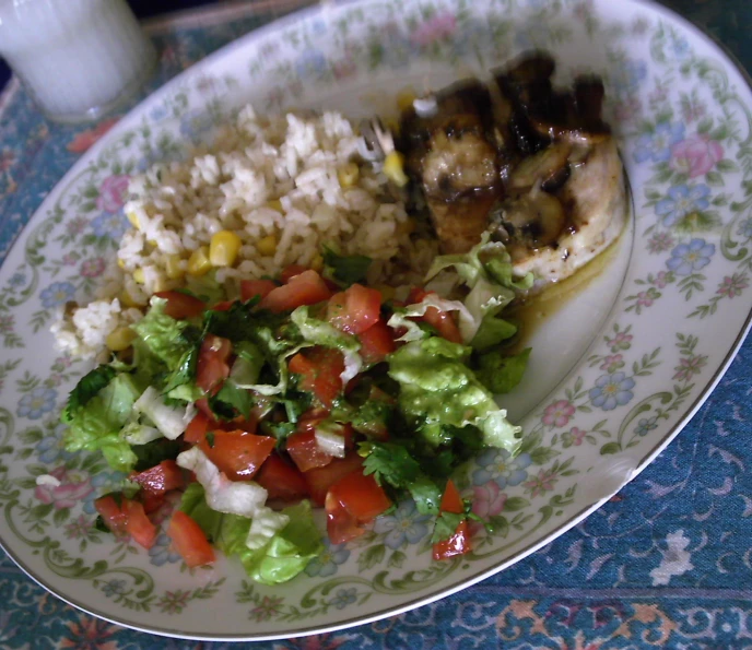 a plate with chicken, rice, and salad on it