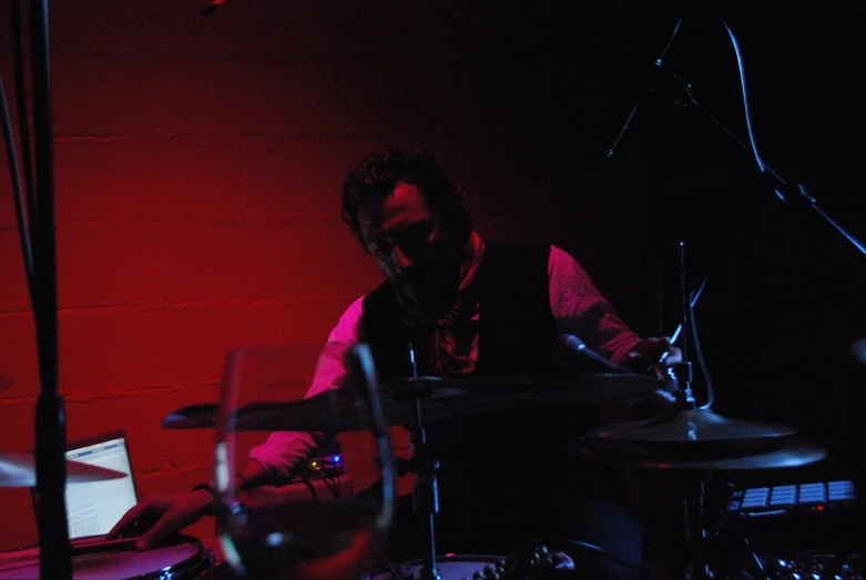 a man is playing drums in front of a red light