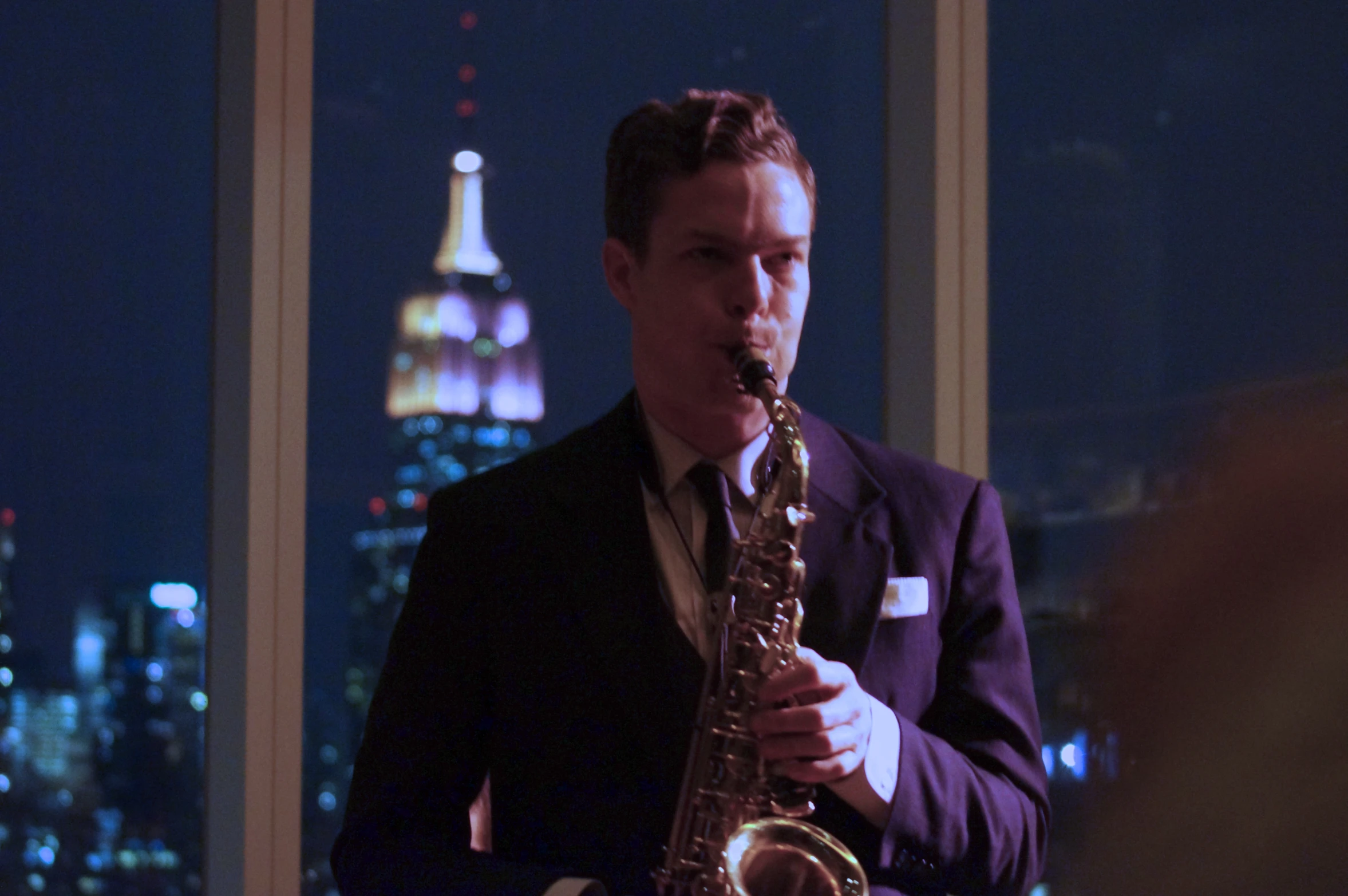 a man is playing on a saxophone in front of the city at night