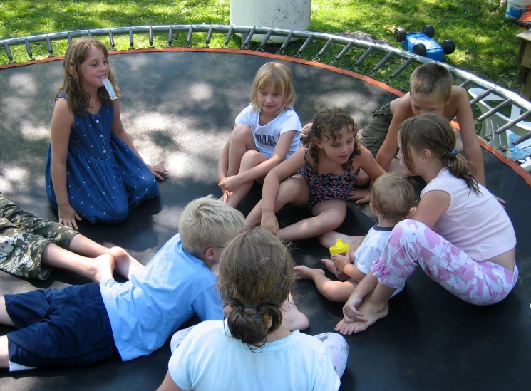 a group of children sitting on top of a trampoline in a park