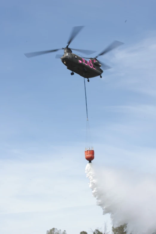 a helicopter lowering a bucket with fire extinguishers