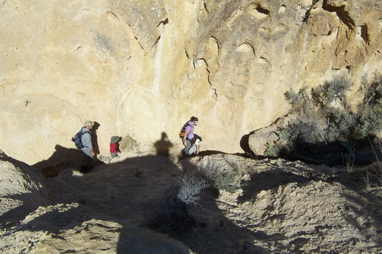 two people hiking along a trail near large rocks