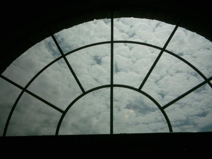 an open arched window with clouds in the sky