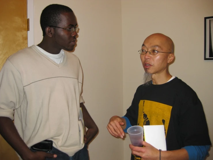 a man with glasses talks with a man in a white shirt