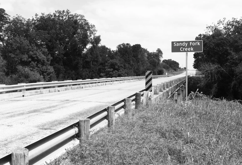 black and white pograph of highway sign on dirt road