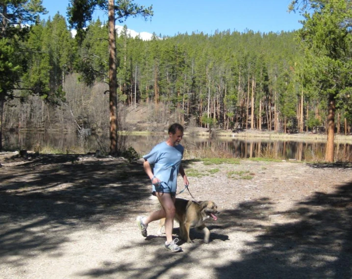 a man walking his dog by a lake