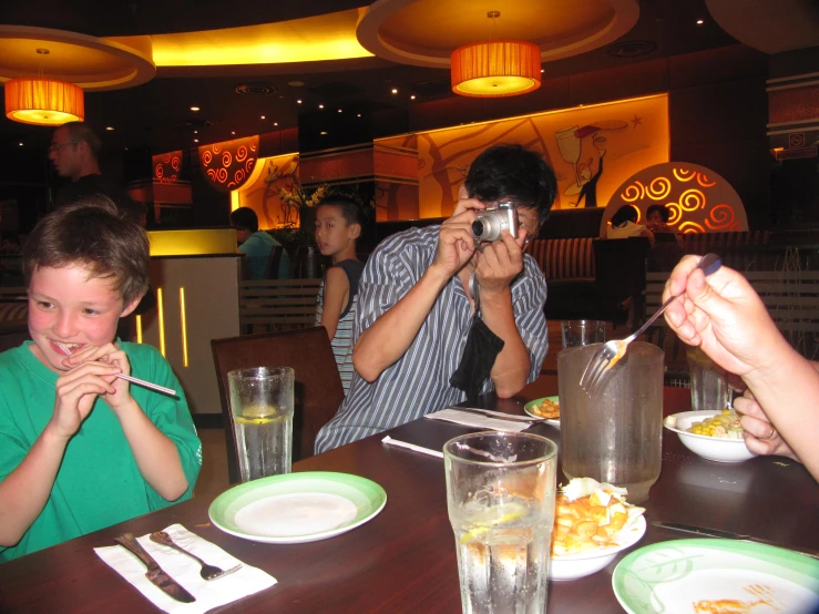 two boys and a woman are eating at the restaurant