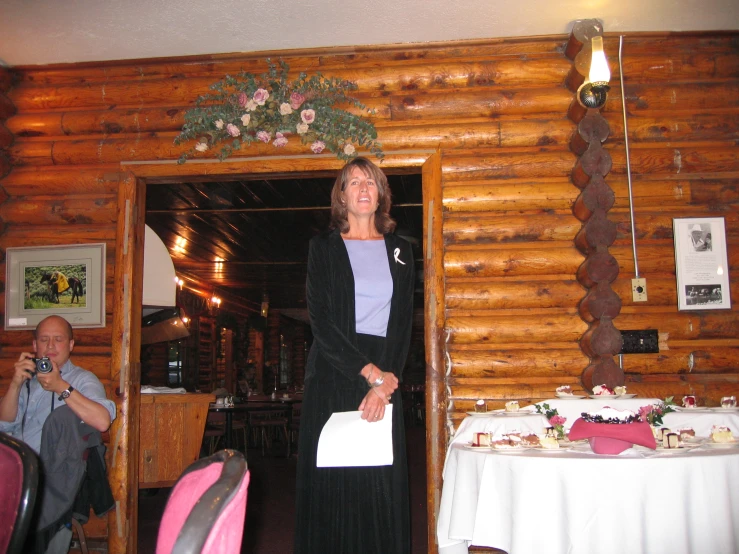 a woman standing in the doorway of a wooden house