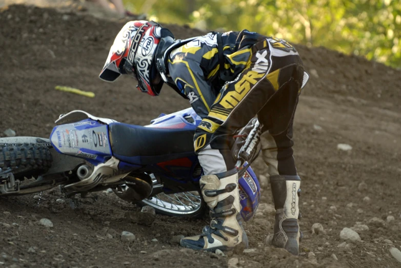 a dirt bike rider bending over on his knees
