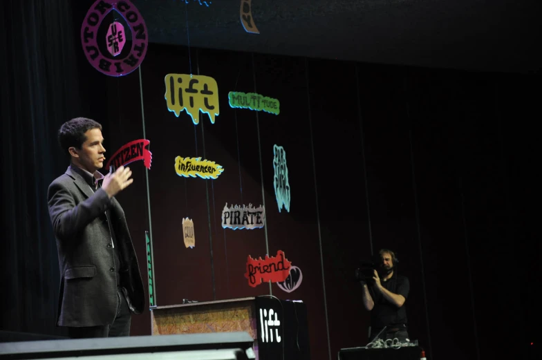 two men are standing on a stage with speakers