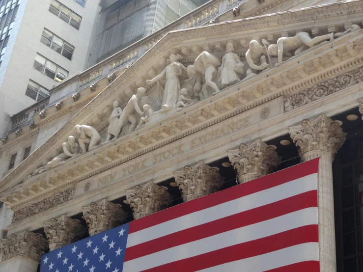 american flag hangs outside of a building with other statues on it