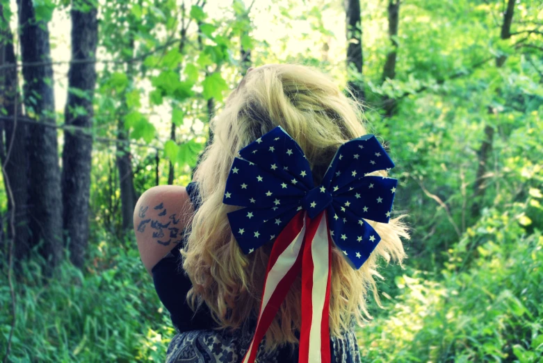 woman wearing a patriotic bow standing in the woods