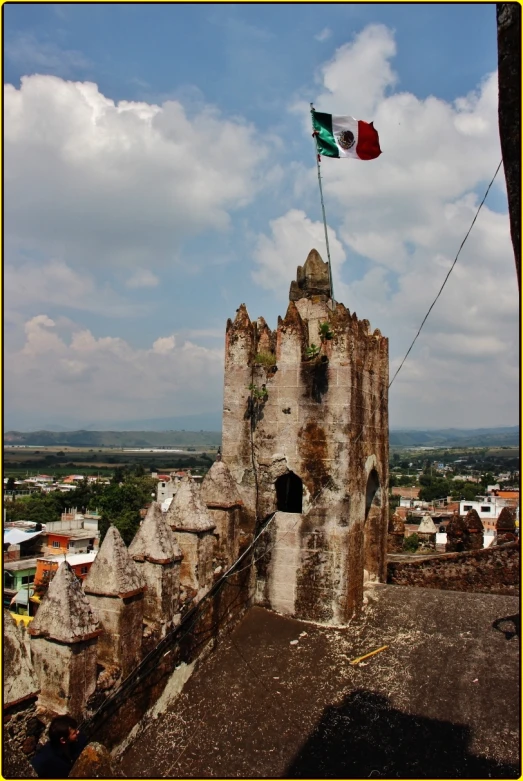 an old castle with a flag and clouds in the background