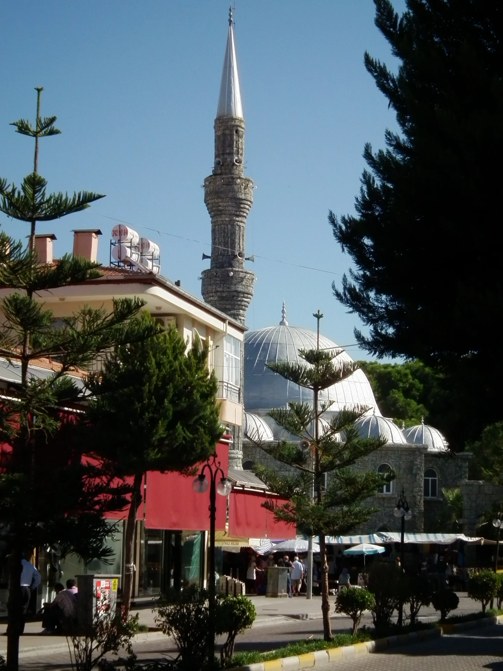 a big clock tower is near some trees and people