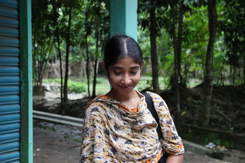 a girl with brown and white blouse holding a black phone