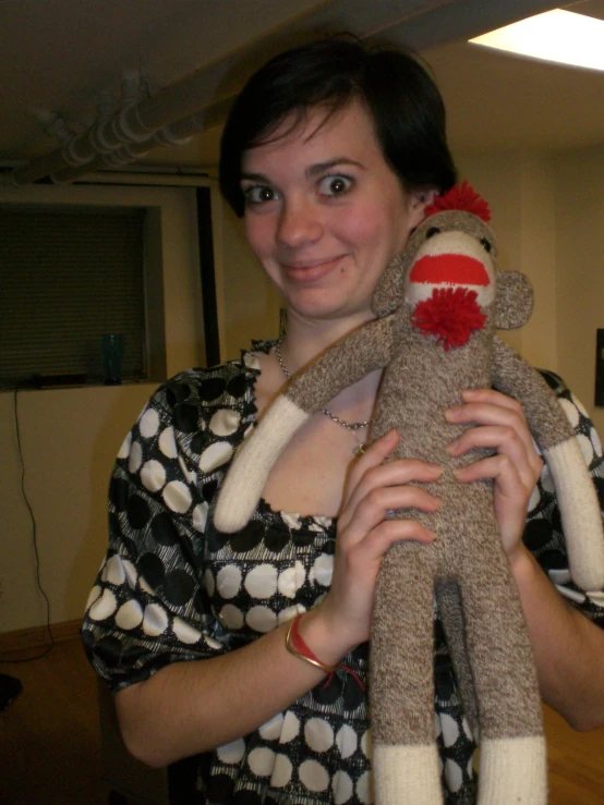 a woman holding a stuffed monkey wearing a necklace