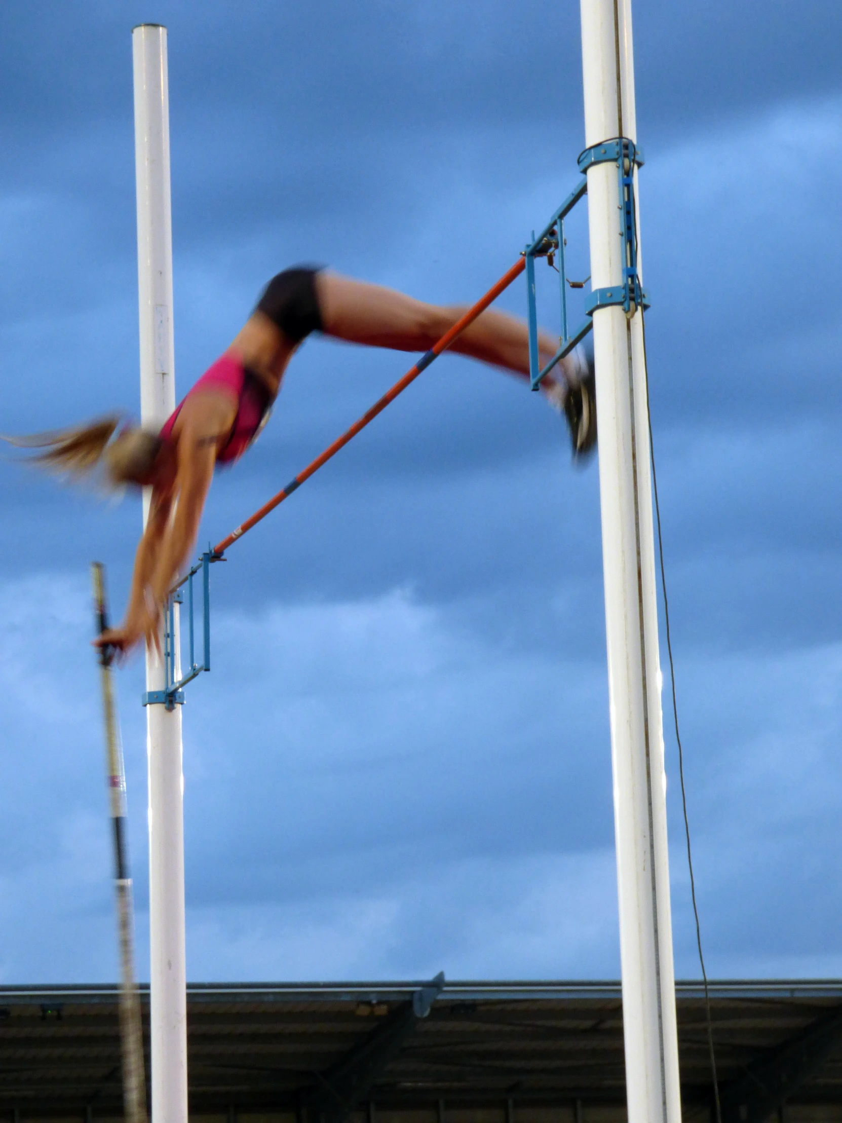 female aerial acrobatics with poles in front of blue sky