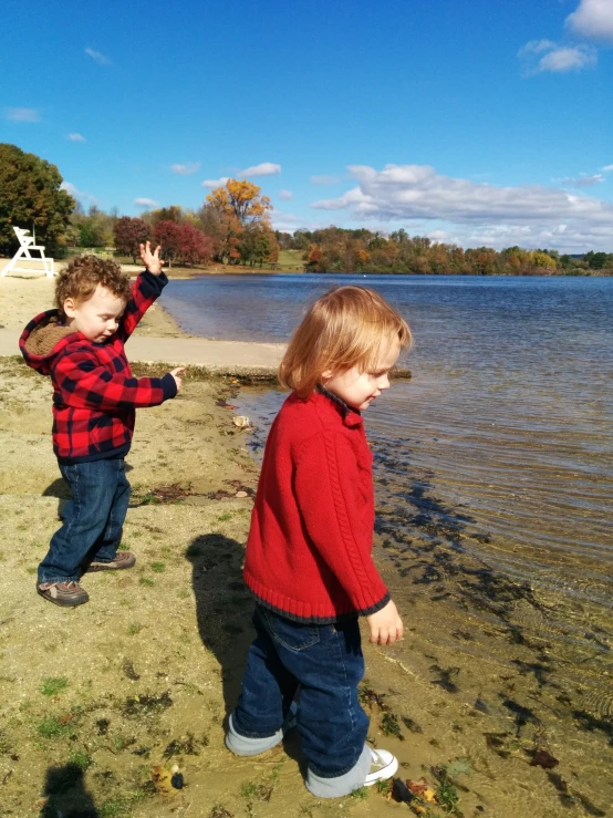 two small children playing by the water on a sunny day