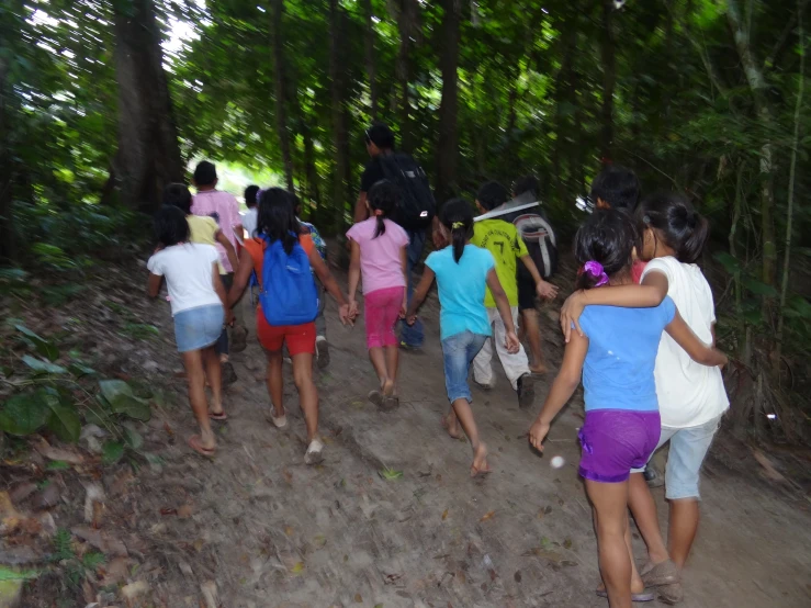 a group of s in colorful shirts walking down a trail