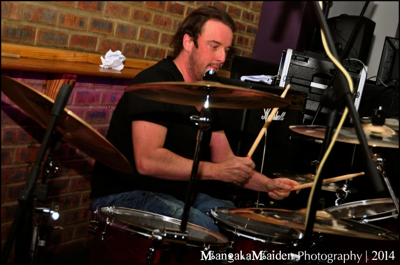 a man sitting down playing drums in front of a microphone