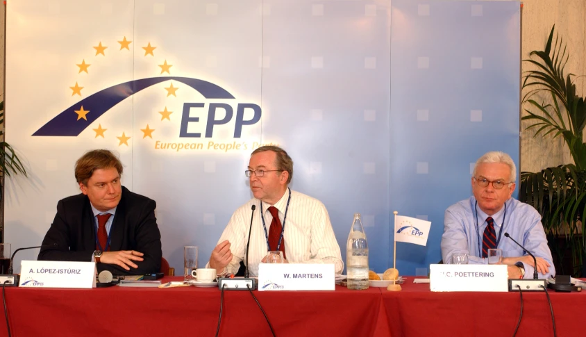 four men sitting at a table in front of a banner