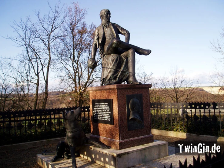 a statue of a man sitting next to a bronze dog