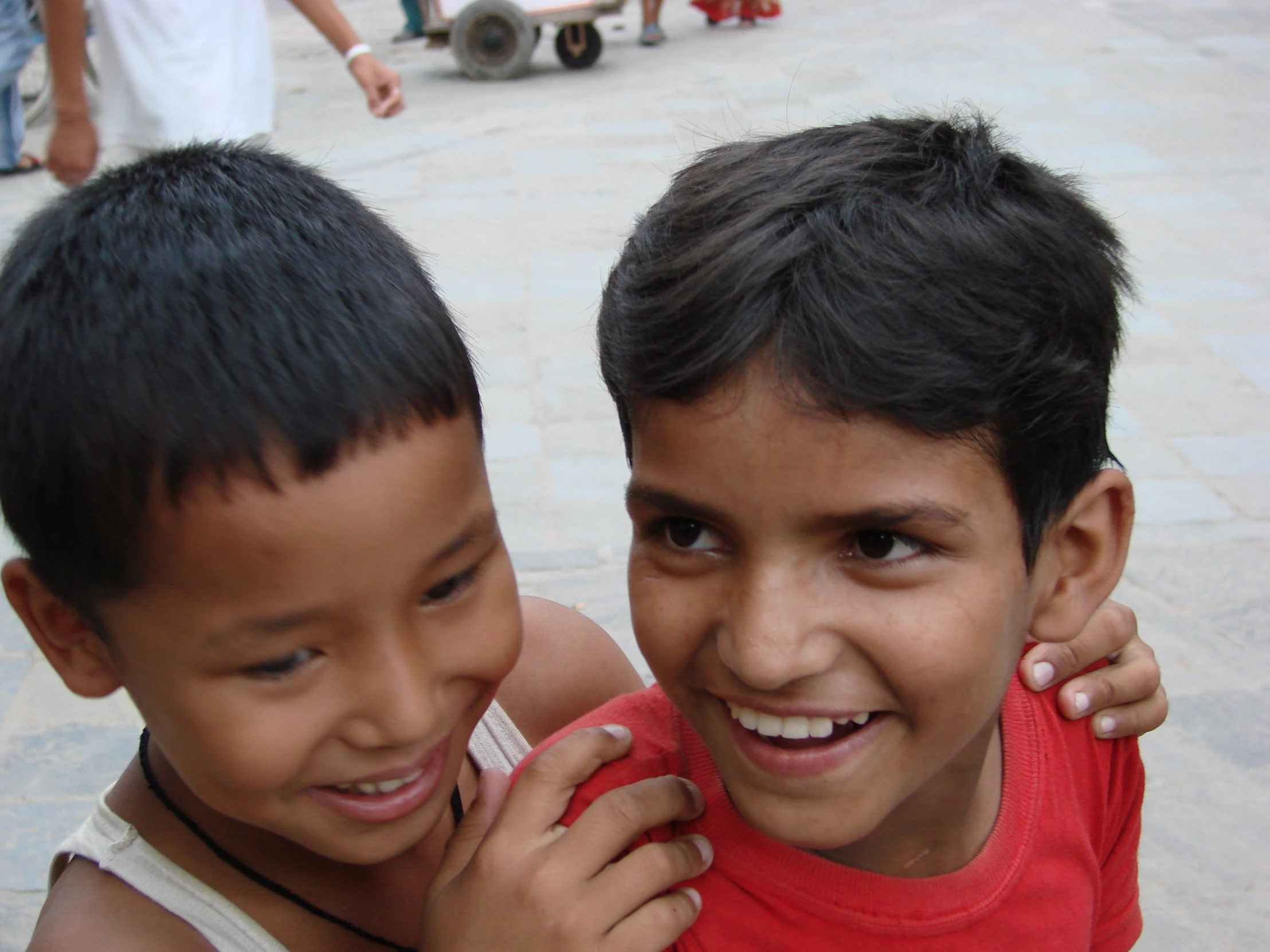 two boys are smiling while one of them has his arm around the other