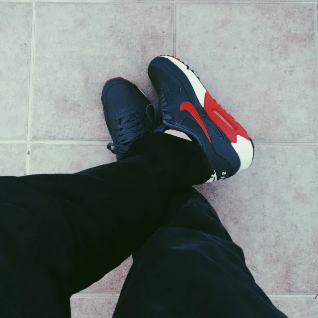 the feet of a person wearing blue and red sneakers