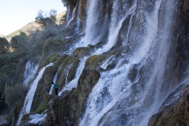 person in water near large waterfall with green background