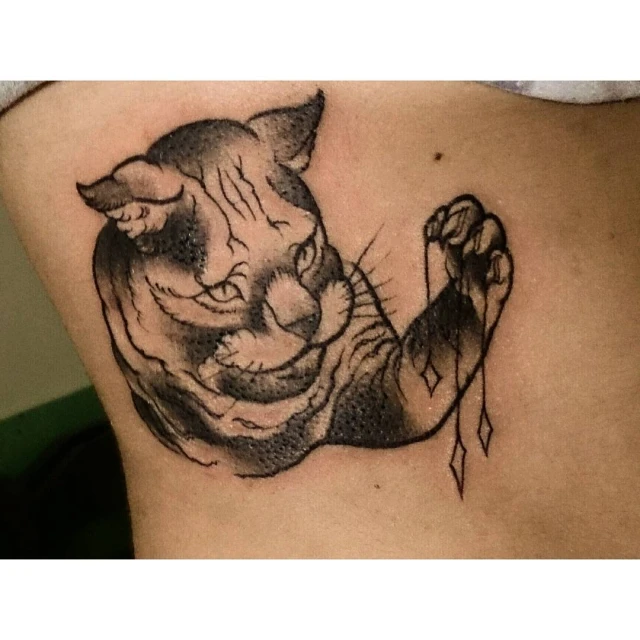 a tattoo of a cat that is holding a ball