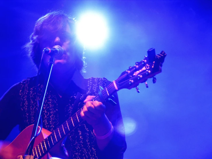 man in concert outfit playing a guitar on stage