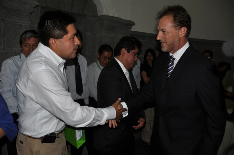 two men shaking hands in front of a crowd of people