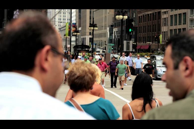 people walk down a city street at a crosswalk