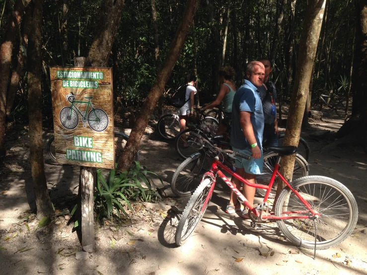 a man standing in front of a parked bicycle next to a sign