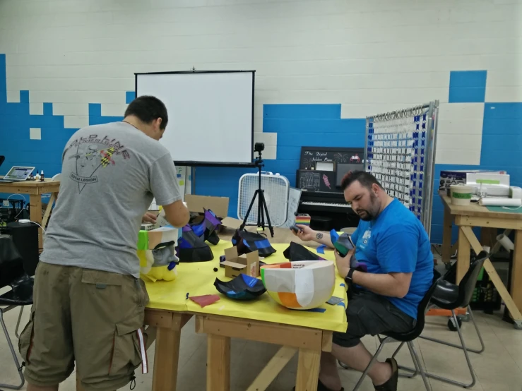 a pair of men work on shoes at a table