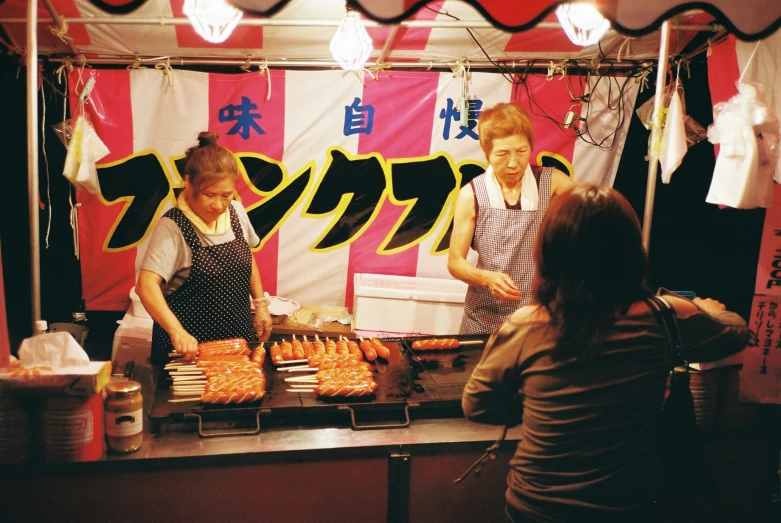 two people preparing food on an oriental stall