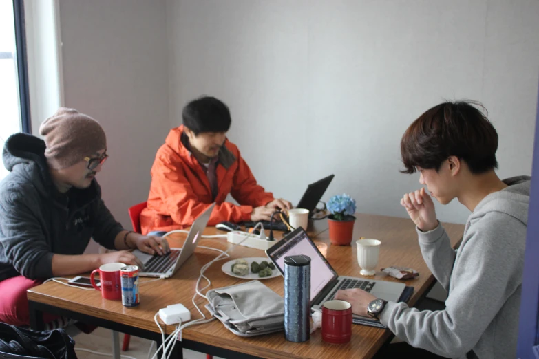 three people work on laptops around a small table