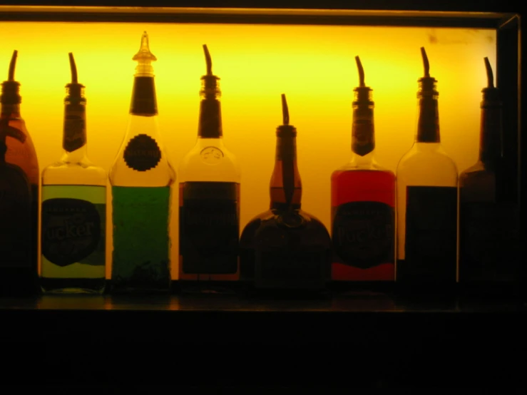 six bottles of liquor are lined up against a yellow wall